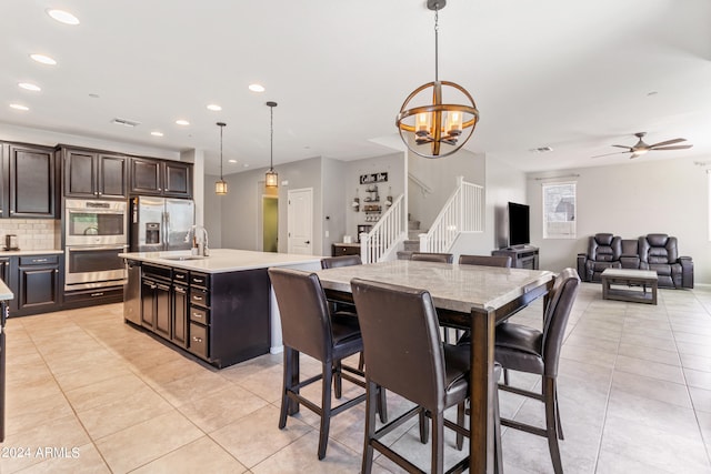 dining area featuring ceiling fan with notable chandelier, light tile patterned floors, and sink