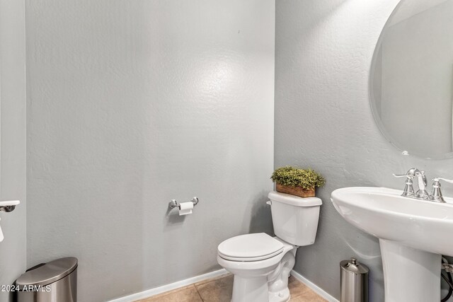 bathroom with toilet, sink, and tile patterned flooring