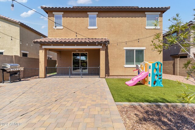 back of property featuring a playground, a patio area, and a lawn