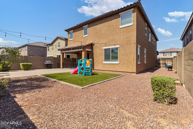 21243 W Coronado Rd, Buckeye, AZ 85396 - rear view of property featuring a playground, stucco siding, a fenced backyard, a patio, and a yard