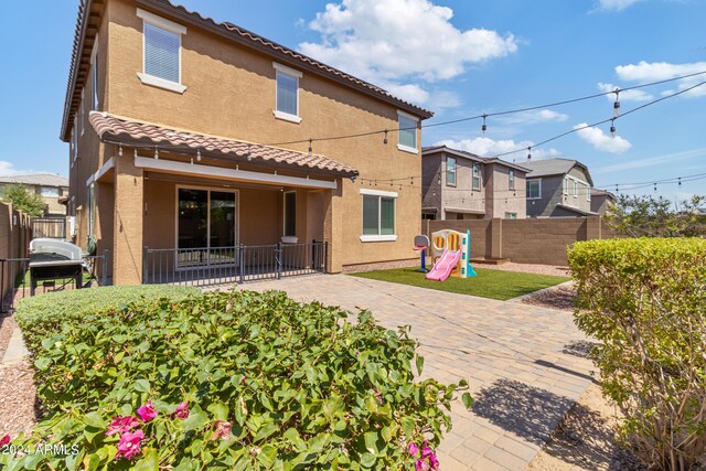 back of property with a playground and a patio