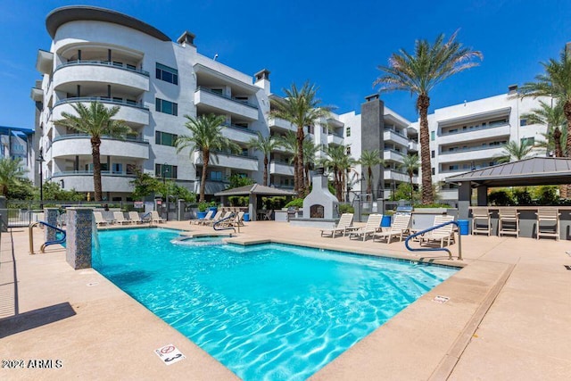 view of pool featuring a fireplace, a gazebo, and a patio