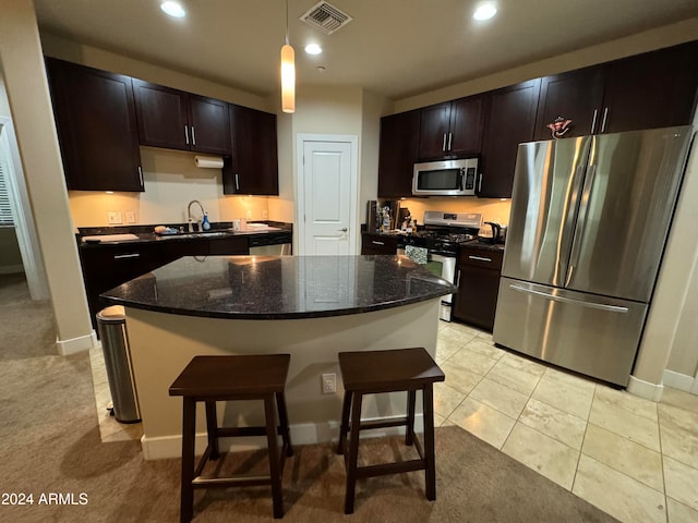 kitchen featuring sink, stainless steel appliances, dark stone counters, and light carpet