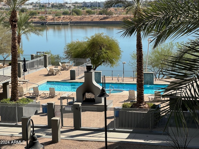 view of pool featuring a water view, a patio, and a hot tub