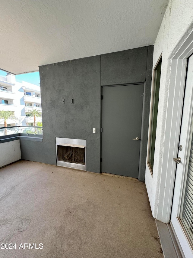 unfurnished living room with a large fireplace, light colored carpet, and a textured ceiling