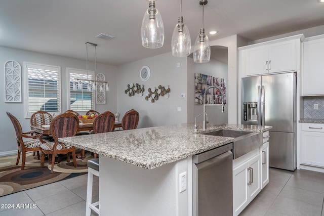 kitchen featuring backsplash, white cabinets, stainless steel appliances, and an island with sink