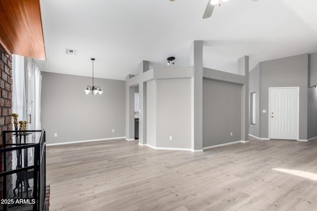 unfurnished living room featuring vaulted ceiling, a fireplace, ceiling fan with notable chandelier, and light wood-type flooring