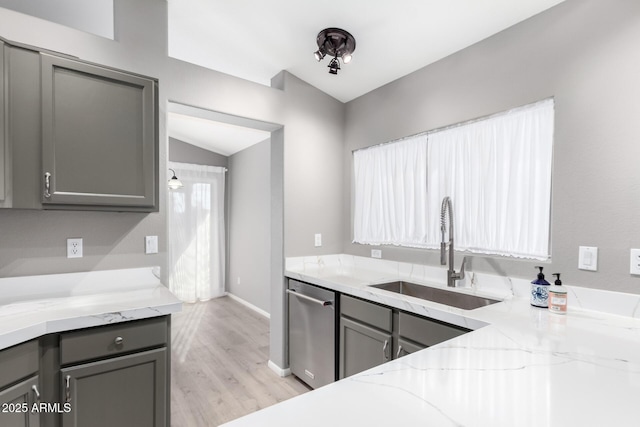 kitchen with light stone countertops, vaulted ceiling, sink, dishwasher, and gray cabinets