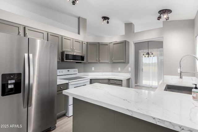 kitchen with gray cabinetry, sink, pendant lighting, a chandelier, and appliances with stainless steel finishes