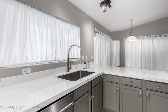 kitchen with gray cabinetry, sink, vaulted ceiling, light stone countertops, and decorative light fixtures