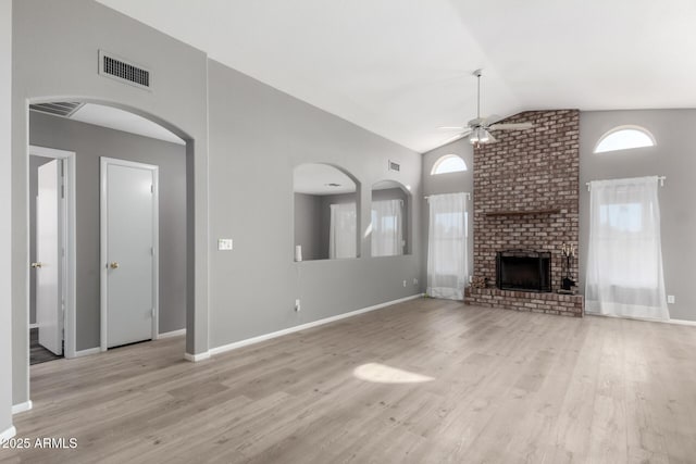 unfurnished living room featuring ceiling fan, light wood-type flooring, vaulted ceiling, and a brick fireplace