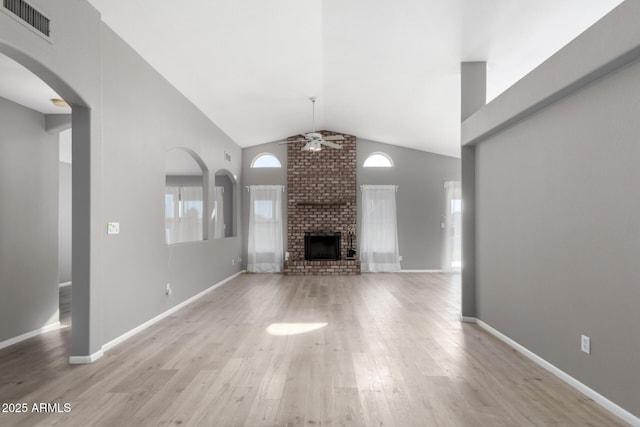 unfurnished living room featuring ceiling fan, light hardwood / wood-style floors, vaulted ceiling, and a brick fireplace