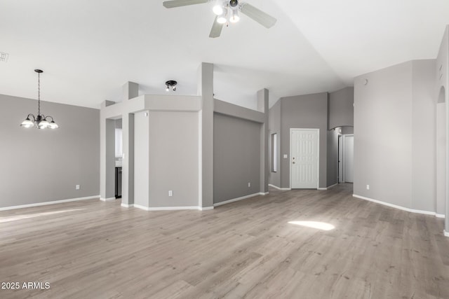 unfurnished living room featuring ceiling fan with notable chandelier, light wood-type flooring, and high vaulted ceiling