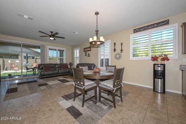 tiled dining space featuring ceiling fan with notable chandelier and plenty of natural light