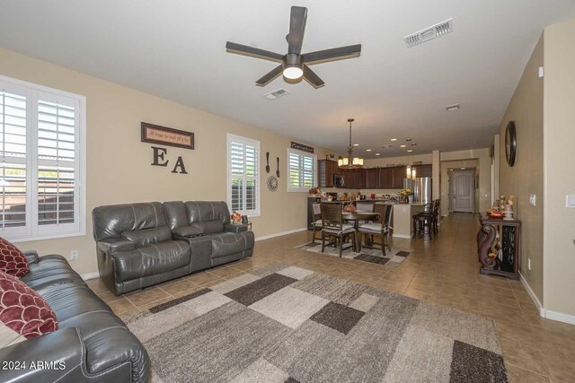 living room with ceiling fan with notable chandelier and light tile patterned floors