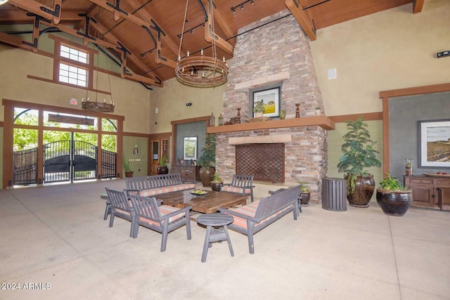 interior space with a stone fireplace, beamed ceiling, concrete flooring, and high vaulted ceiling