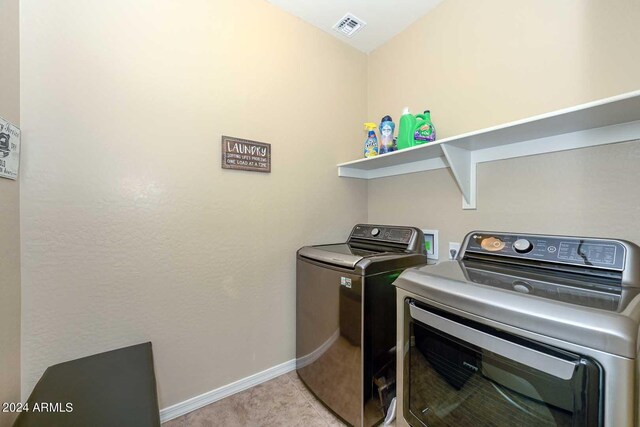 clothes washing area with light carpet and washer and dryer