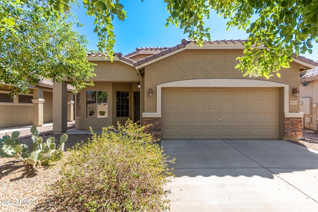 view of front facade featuring an attached garage, stucco siding, concrete driveway, stone siding, and a tile roof