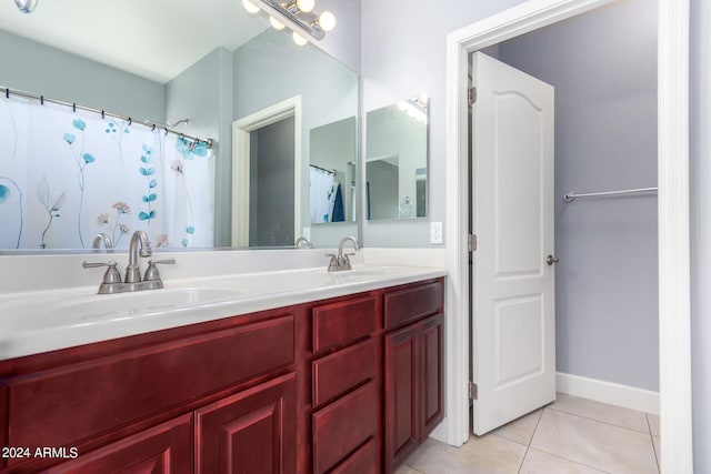 bathroom featuring tile patterned flooring, double vanity, baseboards, and a sink