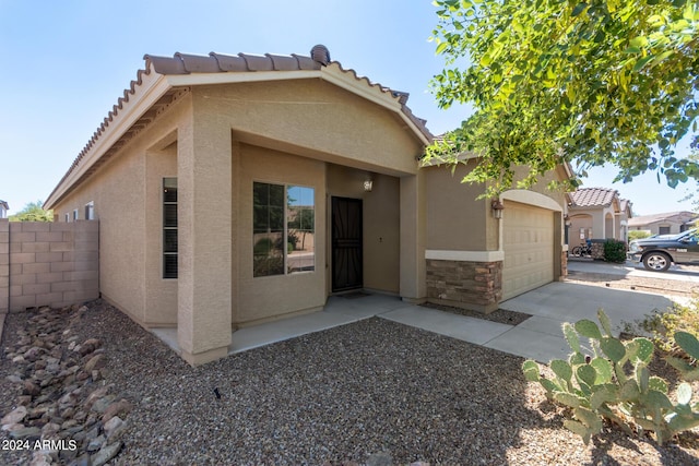 view of front of property featuring fence, concrete driveway, a tile roof, stucco siding, and stone siding