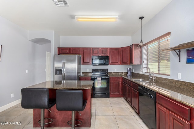 kitchen featuring visible vents, dark brown cabinets, a kitchen island, black appliances, and a sink