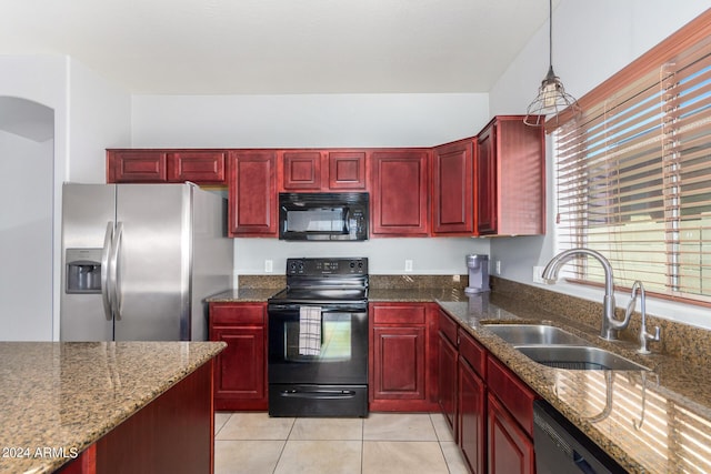 kitchen featuring black appliances, a sink, dark stone counters, light tile patterned floors, and dark brown cabinets