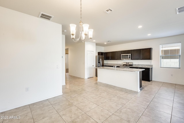 kitchen with visible vents, a center island with sink, appliances with stainless steel finishes, and a notable chandelier