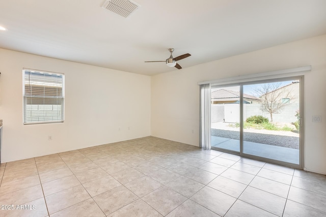 spare room with light tile patterned floors, ceiling fan, visible vents, and a wealth of natural light