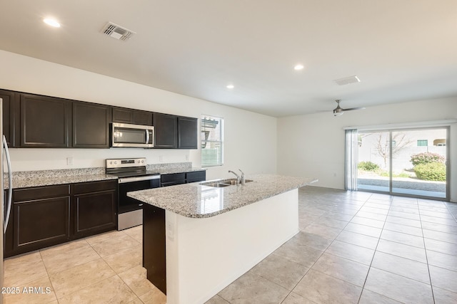 kitchen with light stone counters, light tile patterned floors, stainless steel appliances, visible vents, and a sink