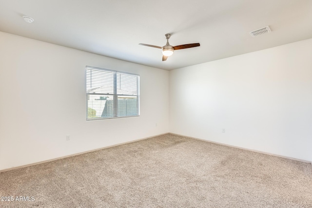 empty room featuring a ceiling fan, visible vents, and carpet flooring