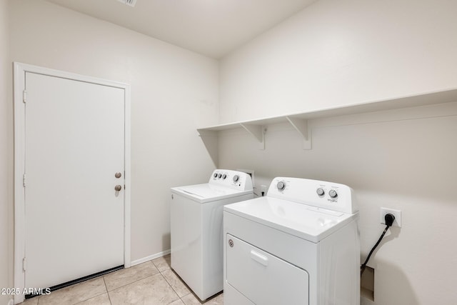 washroom featuring washing machine and dryer, laundry area, and light tile patterned floors