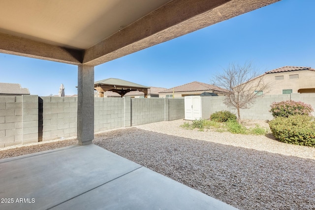 view of patio with an outbuilding, a shed, and a fenced backyard