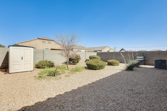 view of yard with an outbuilding, central AC, a fenced backyard, and a shed