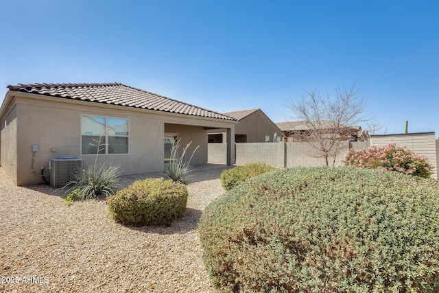 rear view of house featuring central air condition unit, a tile roof, fence, and stucco siding