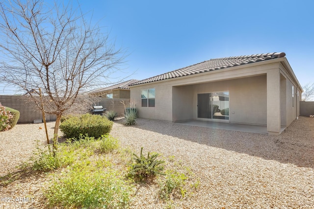 rear view of property with a tile roof, fence, a patio, and stucco siding