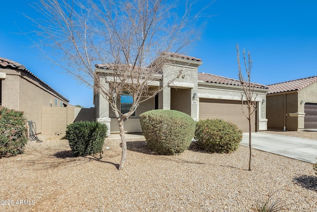 mediterranean / spanish home featuring driveway, a tile roof, an attached garage, fence, and stucco siding