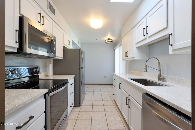 kitchen with light tile patterned flooring, appliances with stainless steel finishes, white cabinetry, and sink