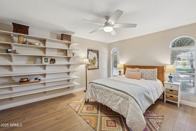 bedroom with light wood finished floors, baseboards, and a ceiling fan