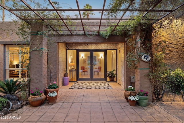 exterior entry at dusk featuring french doors and stucco siding