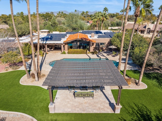 back of house featuring a patio, an outdoor pool, solar panels, and a yard