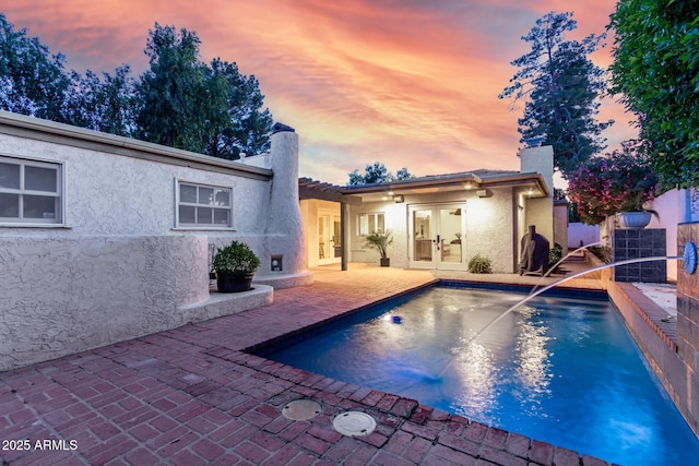 106 E Echo Ln, Phoenix, AZ 85020 - back of house at dusk with french doors, a patio, stucco siding, a fenced in pool, and a chimney