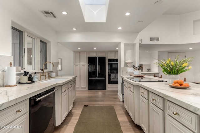 106 E Echo Ln, Phoenix, AZ 85020 - kitchen featuring a sink, light wood-type flooring, visible vents, black appliances, and light stone counters