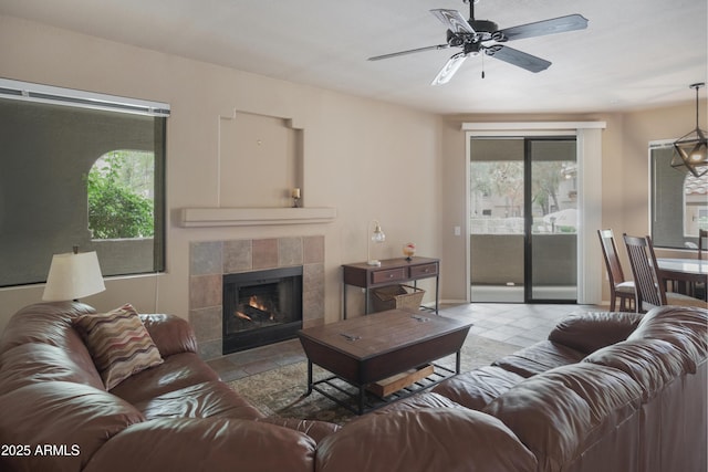 living room with plenty of natural light, ceiling fan, a tile fireplace, and baseboards