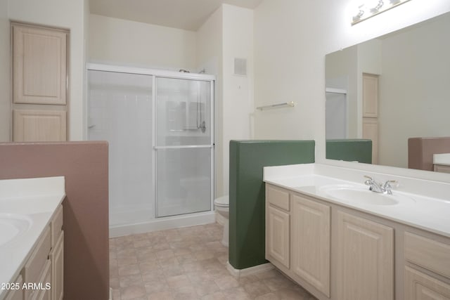 bathroom featuring two vanities, a stall shower, and toilet