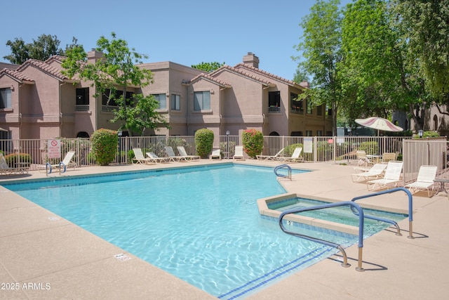 view of pool featuring fence, a patio, and a pool with connected hot tub