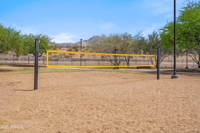 view of home's community with volleyball court, a mountain view, and fence