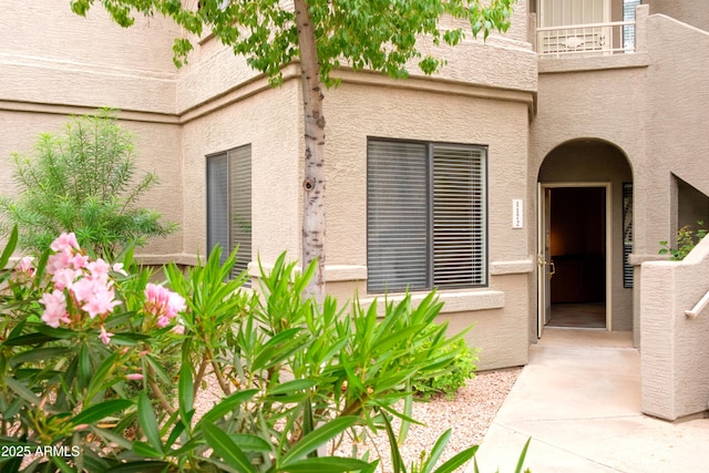 view of exterior entry featuring stucco siding and a balcony