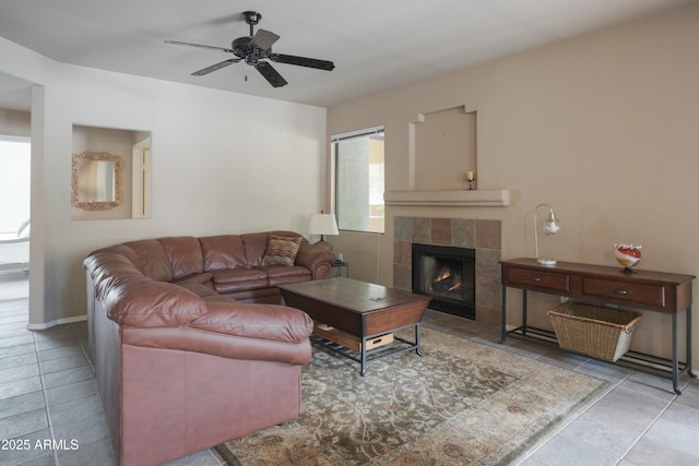 living area with a tile fireplace, a ceiling fan, and tile patterned floors