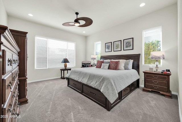 bedroom with ceiling fan, light colored carpet, and multiple windows