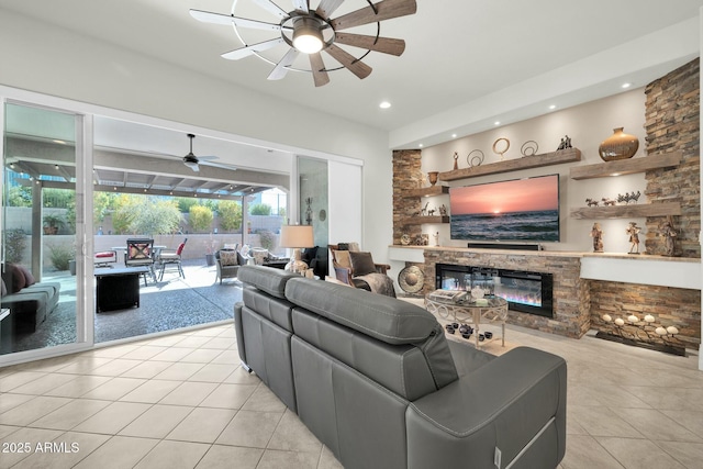 tiled living room featuring a stone fireplace and ceiling fan